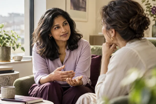 Two women having a relaxed, attentive conversation beside a window